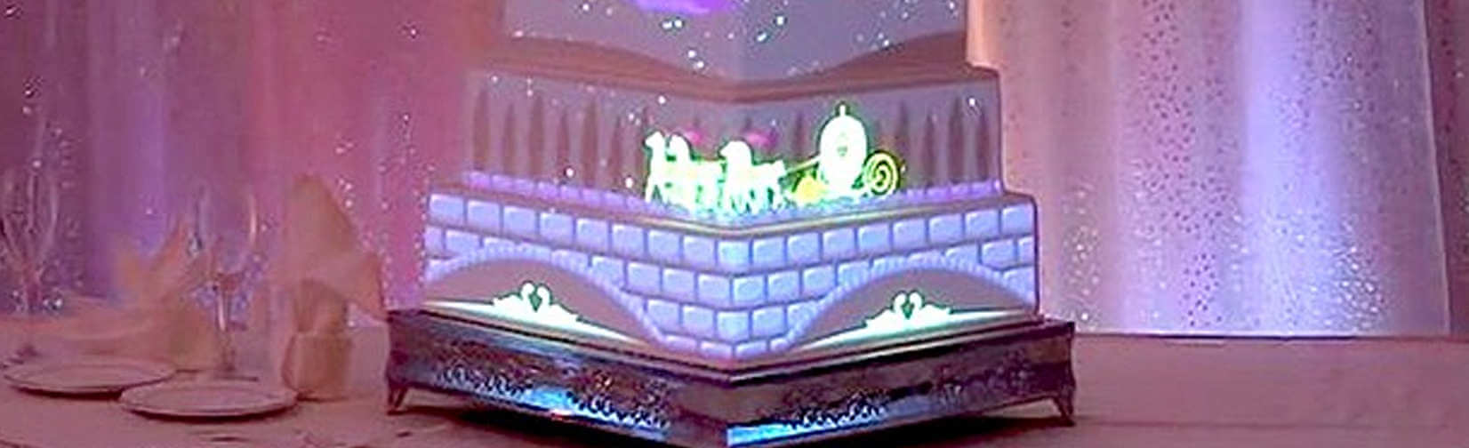 a tiered wedding cake with animations projected onto its surface.
